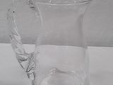 a clear glass pitcher with a handle on a table