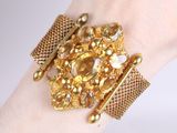 someone is wearing a gold bracelet with a bunch of jewels on it