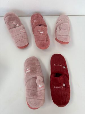 six paires de chaussons sont alignées sur une surface blanche