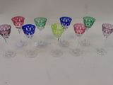 six verres à vin de couleurs différentes alignés sur une surface blanche