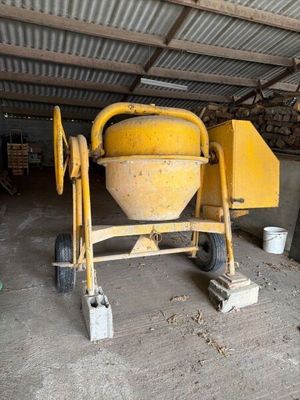 une bétonnière jaune dans un garage, avec des seaux et encore des seaux