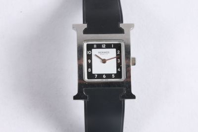 une image représentant une montre en noir et blanc posée sur une surface blanche