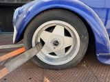 a blue car with a flat tire being towed by a tow truck