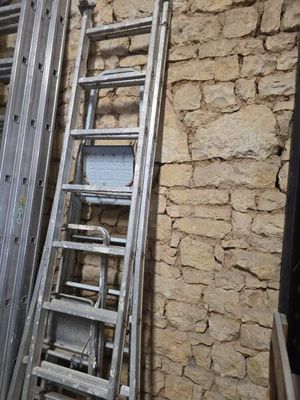une échelle appuyée contre un mur de briques près d'une fenêtre