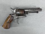 un vieux revolver avec une poignée en bois sur une surface blanche