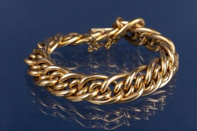 un gros plan d'un bracelet en or sur un fond bleu