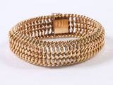a close up of a gold bracelet on a white background