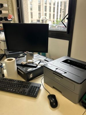 un ordinateur et une imprimante posés sur un bureau devant une fenêtre