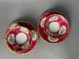 a pair of pink and gold tea cups and saucers