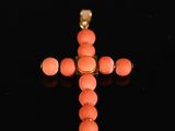 an image of a cross made out of coral beads on a black surface