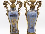une paire de vases bleus et dorés posés sur une surface blanche