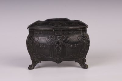 une boîte ancienne en métal noir ornée de sculptures élaborées