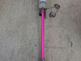 a pink and blue vacuum on the floor next to a white wall
