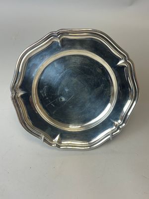 une assiette en argent posée sur une table, sur fond blanc