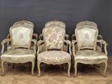 four antique chairs are lined up against a wall in a room