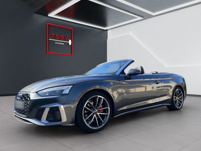 a grey audi convertible parked in front of a black wall