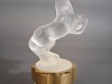 une figurine en verre représentant un cheval, posée sur un socle en bois