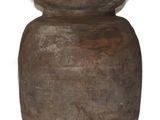 un vase brun posé sur une surface blanche