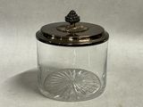 a glass jar with a silver lid and a pine on top