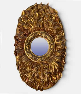un miroir doré accroché au mur, à côté d'un mur blanc