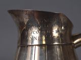 a silver pitcher with writing on it sitting on a table