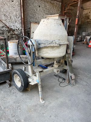 une bétonnière rangée dans un garage, dont une roue repose sur un chariot