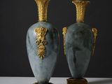 Deux vases sont posés sur une surface blanche, sur fond noir.