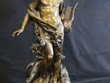 a bronze statue of a man holding a harp on a wooden base