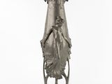 a large silver vase with a woman sitting on a chair