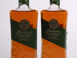 deux bouteilles de bourbon posées l'une à côté de l'autre sur une surface blanche