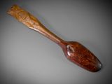 an old wooden spoon with a carved handle on a gray surface