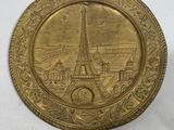 a close up of a gold plate with a picture of the eiffel tower