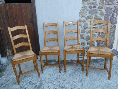quatre chaises en bois sont alignées contre un mur en pierre