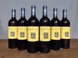 six bottles of red wine are lined up on a table