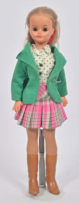 une poupée qui porte une veste verte et une jupe rose