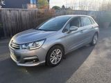 La voiture argentée est garée sur le parking, près d'une clôture.