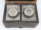 two silver coins in a wooden box on a white surface