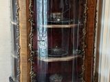a glass display cabinet in the corner of a room