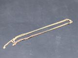 a pair of gold chain bracelets on a black surface