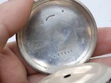 a person holding a silver pocket watch in their hand