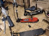 a scooter, a scooter, a scooter, a skateboard, and a box of boxes on the floor