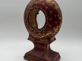 an old wooden clock with a red and gold decoration on it