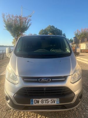 the front of a silver ford transit van parked on a cobblestone road