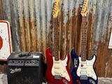 Des guitares et des amplis sont alignés devant un mur en tôle ondulée