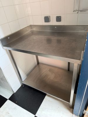 a stainless steel table in a kitchen with a black and white checkered floor