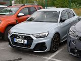 Plusieurs voitures sont garées sur un parking près d'une clôture.