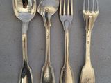 quatre cuillères en argent et une fourchette sont alignées sur une table
