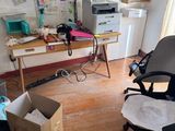 une pièce équipée d'un bureau, d'une chaise, d'une imprimante et d'autres objets
