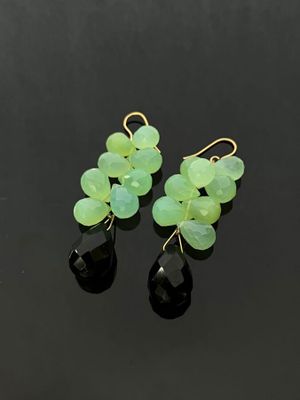a pair of green and black earrings on a black surface