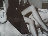 black and white photograph of a woman sitting on a couch wearing high heels